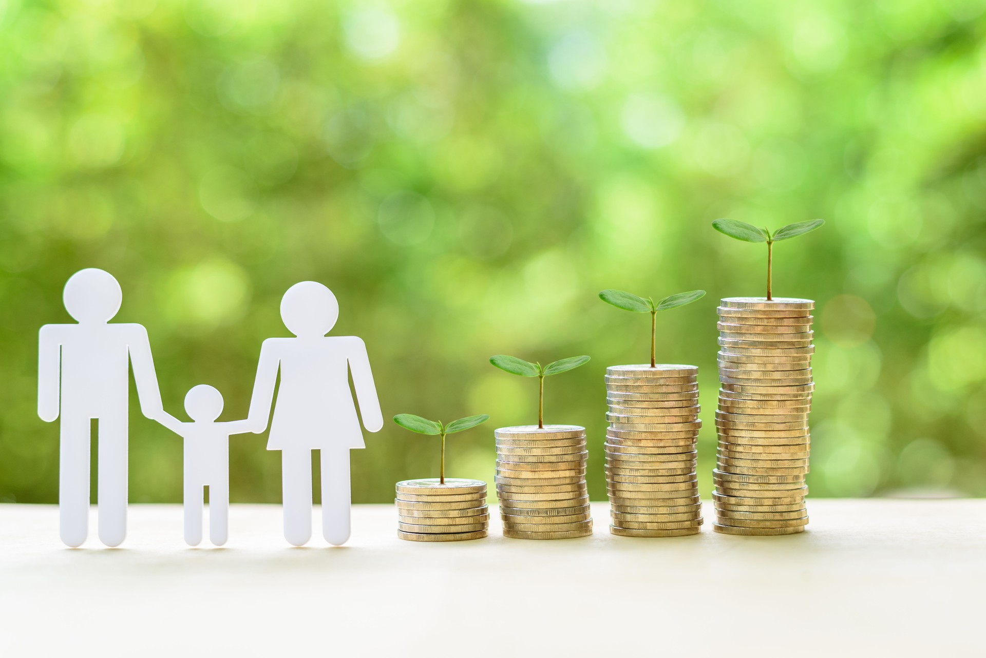 Family members, father, mother and a son, sprouts on stacks of coins on a table.